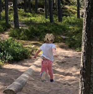 Flicka hoppar långt i en hoppgrop med sand