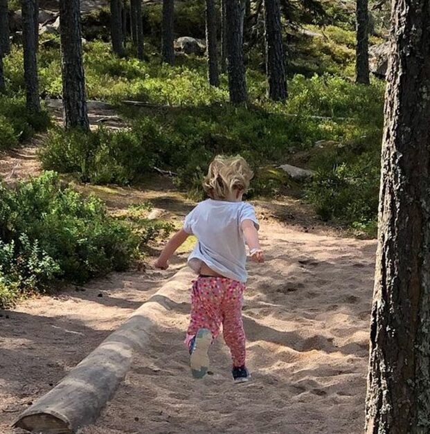Flicka hoppar långt i en hoppgrop med sand.