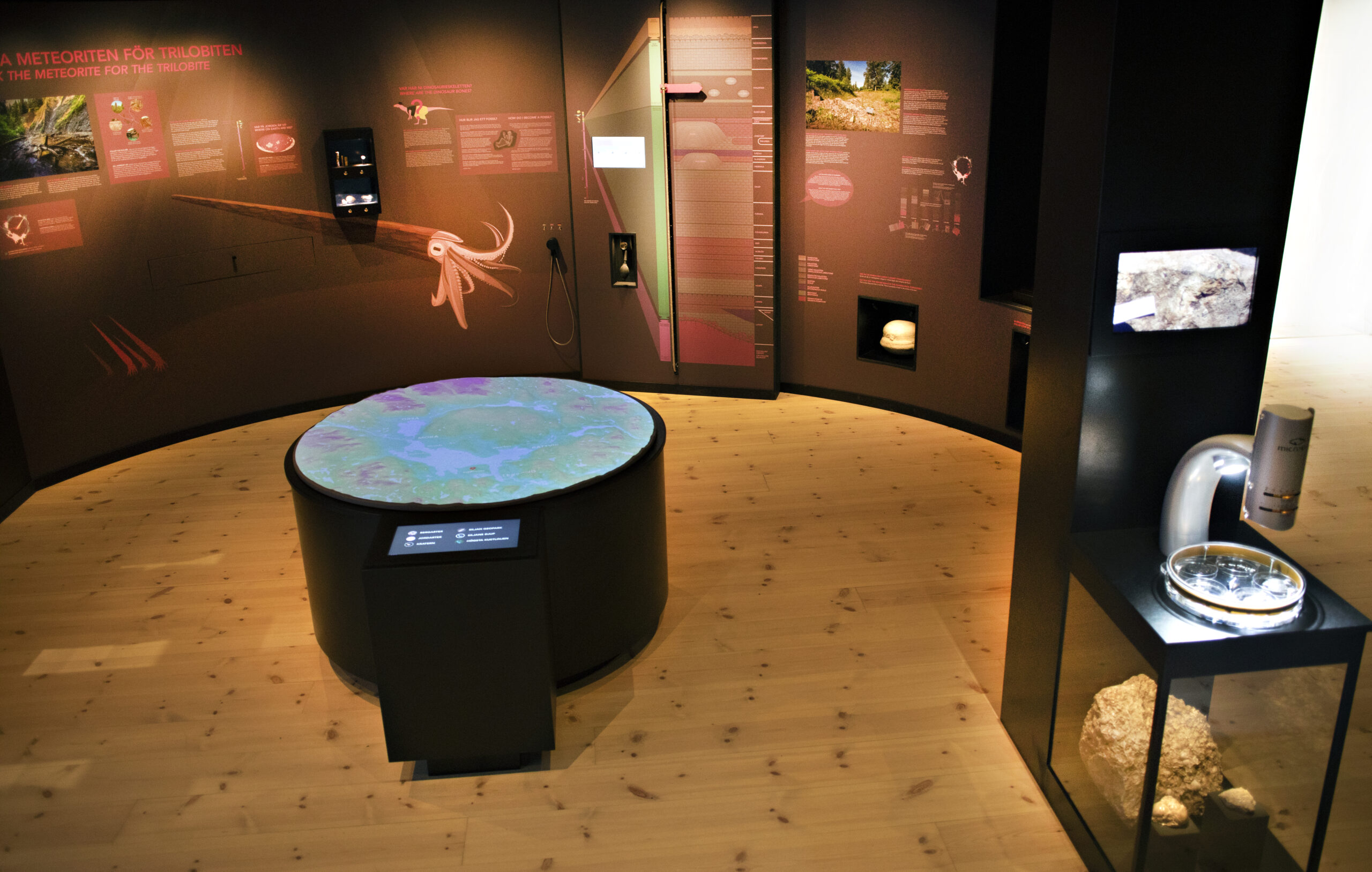 Bild på ingången till utställningen I meteoritens spår med svarta väggar och personer som interagerar med utställningen.