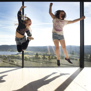 Två flickor hoppar glatt i det inglasade utsiktsdäcket på utsiktstornet.