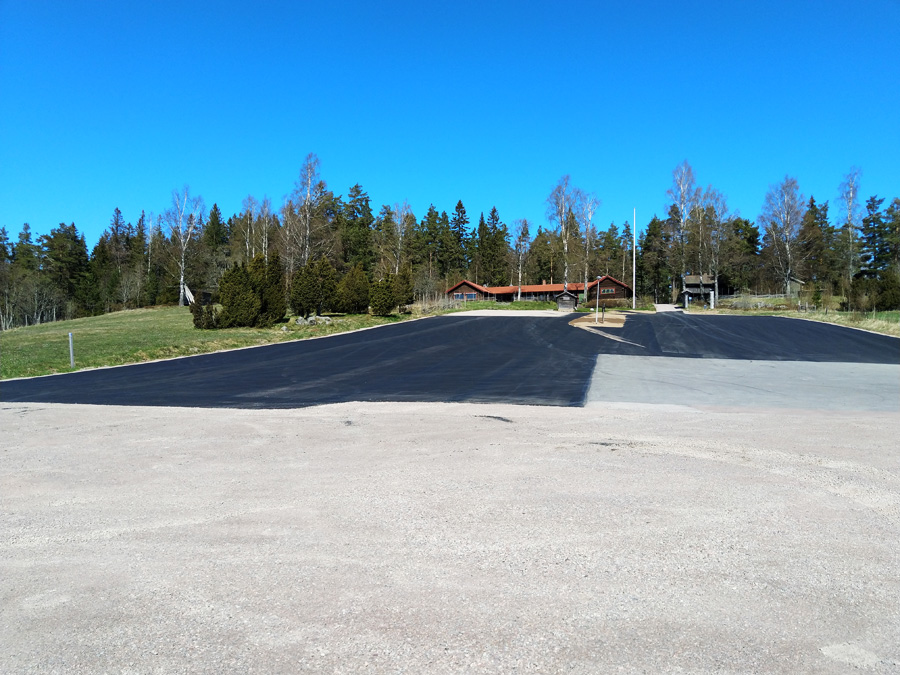En stor parkering där ny asfalt är lagd över en stor del av parkeringen.