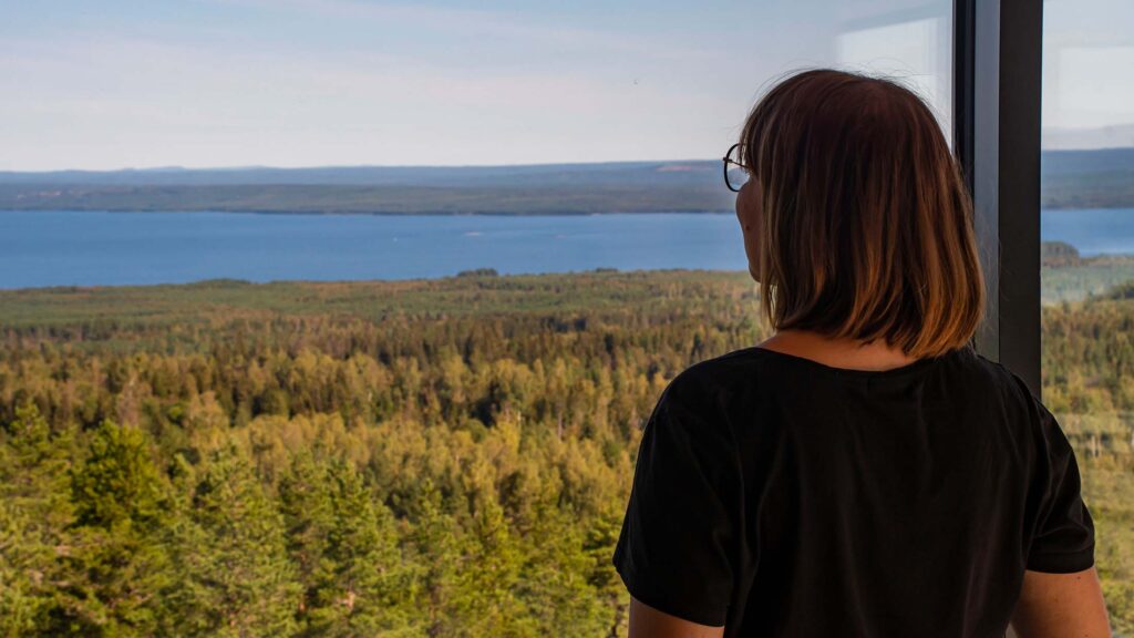 Kvinna blickar ut över utsikten från tornets inglasade däck.