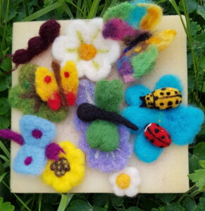 Färgglada fjärilar, blommor och nyckelpigor i tovad ull.